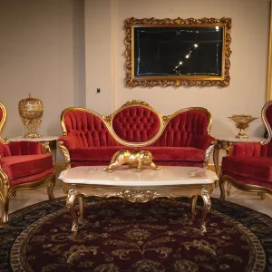 Lisette Victorian salon Living Room from a front facing angle, featuring the sofa and 2 chairs in gold and red velvet with accompanying coffee table and end tables and mirror on the wall.